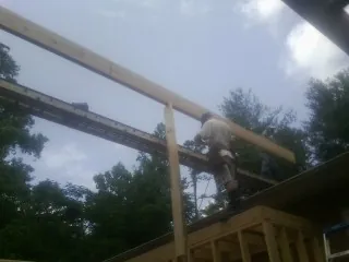 Carpenter setting a ridge beam over a new addition frame — Ice Dam Removal by Roofing Brothers in Kenedy