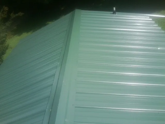 New green metal panels meeting at the ridge of a roof — Flat Roof Repair work by our crew in Kenedy