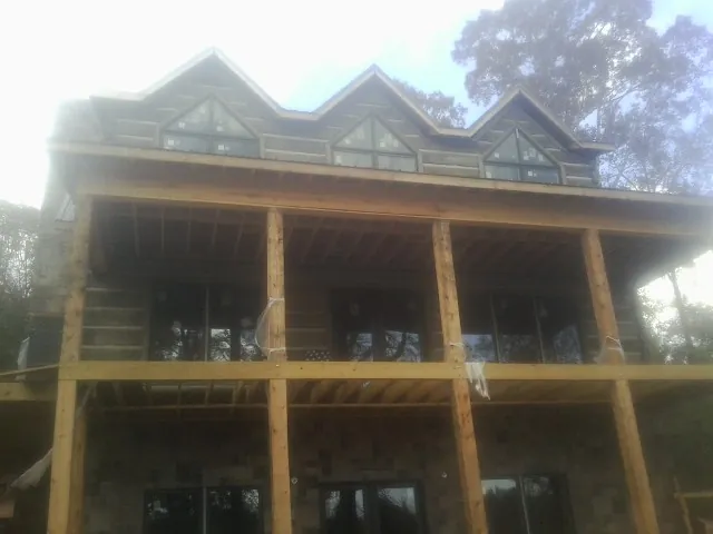 Dormers and porch framing on a large log home under construction — Roof Coating work by our crew in Kenedy