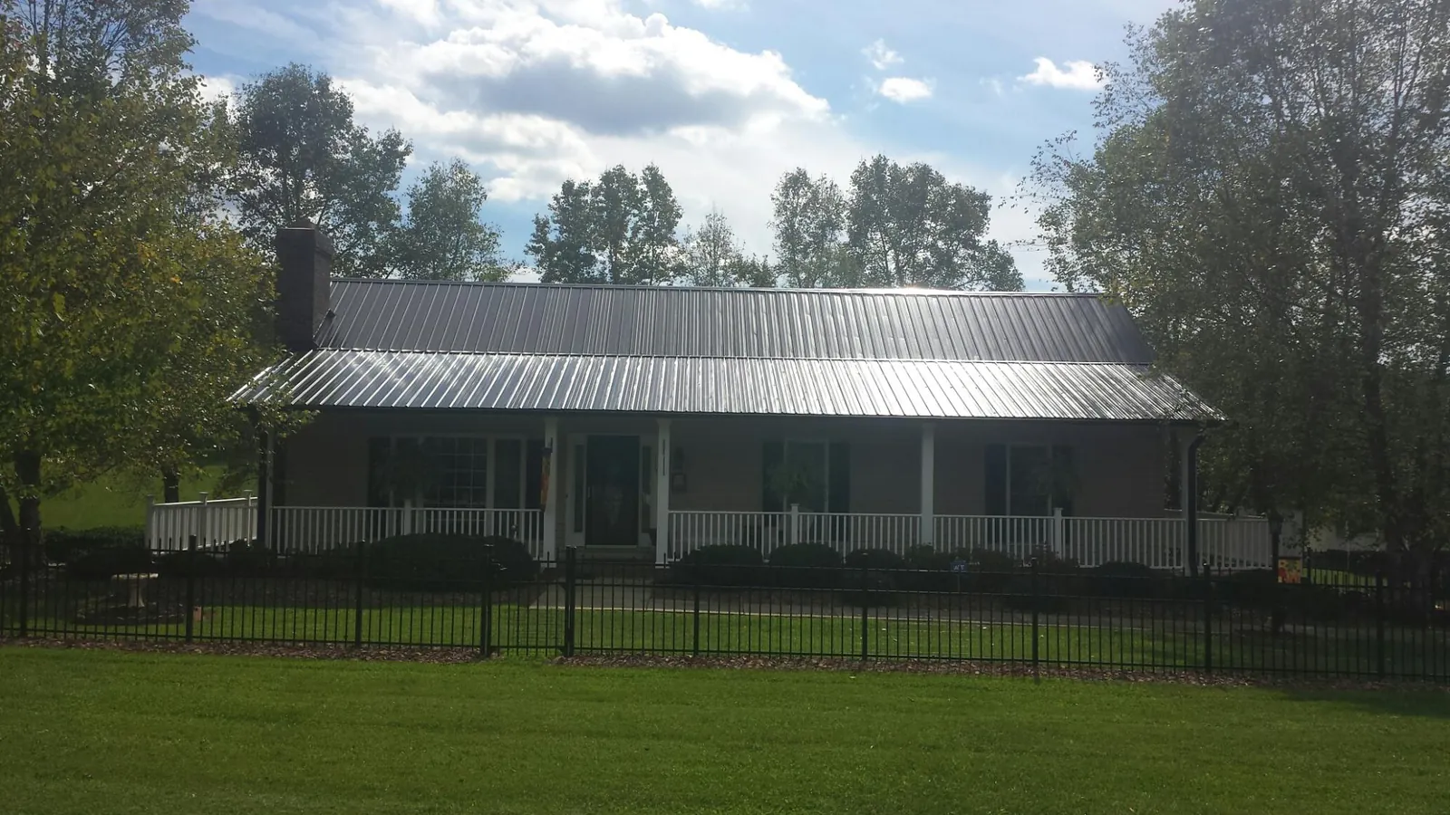 Gray metal roof on a brick ranch with a full width front porch — Gutter Guard Installation work by our crew in Kenedy