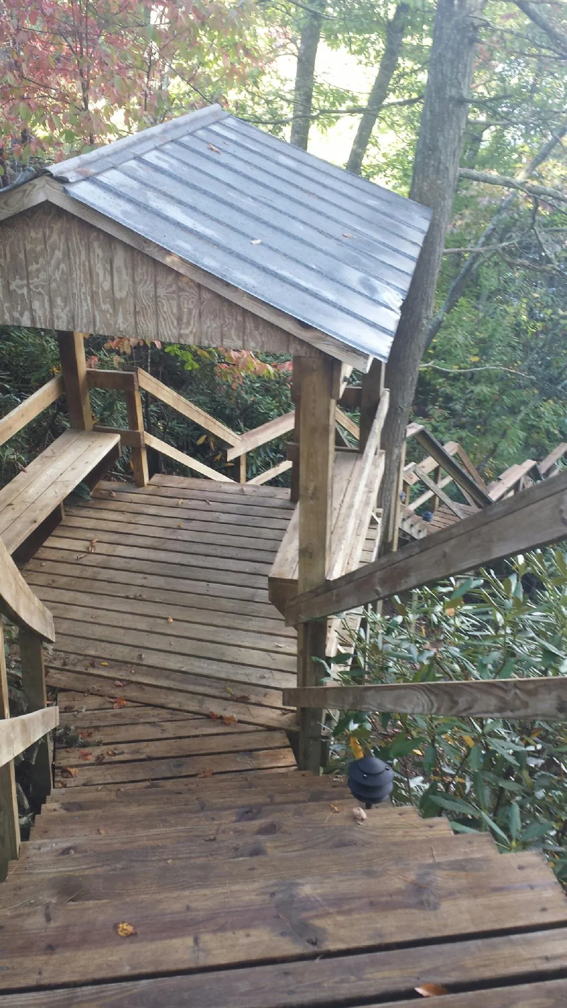 Metal roofed shelter over wooden steps on a wooded walkway — Skylight Repair & Installation work by our crew in Kenedy