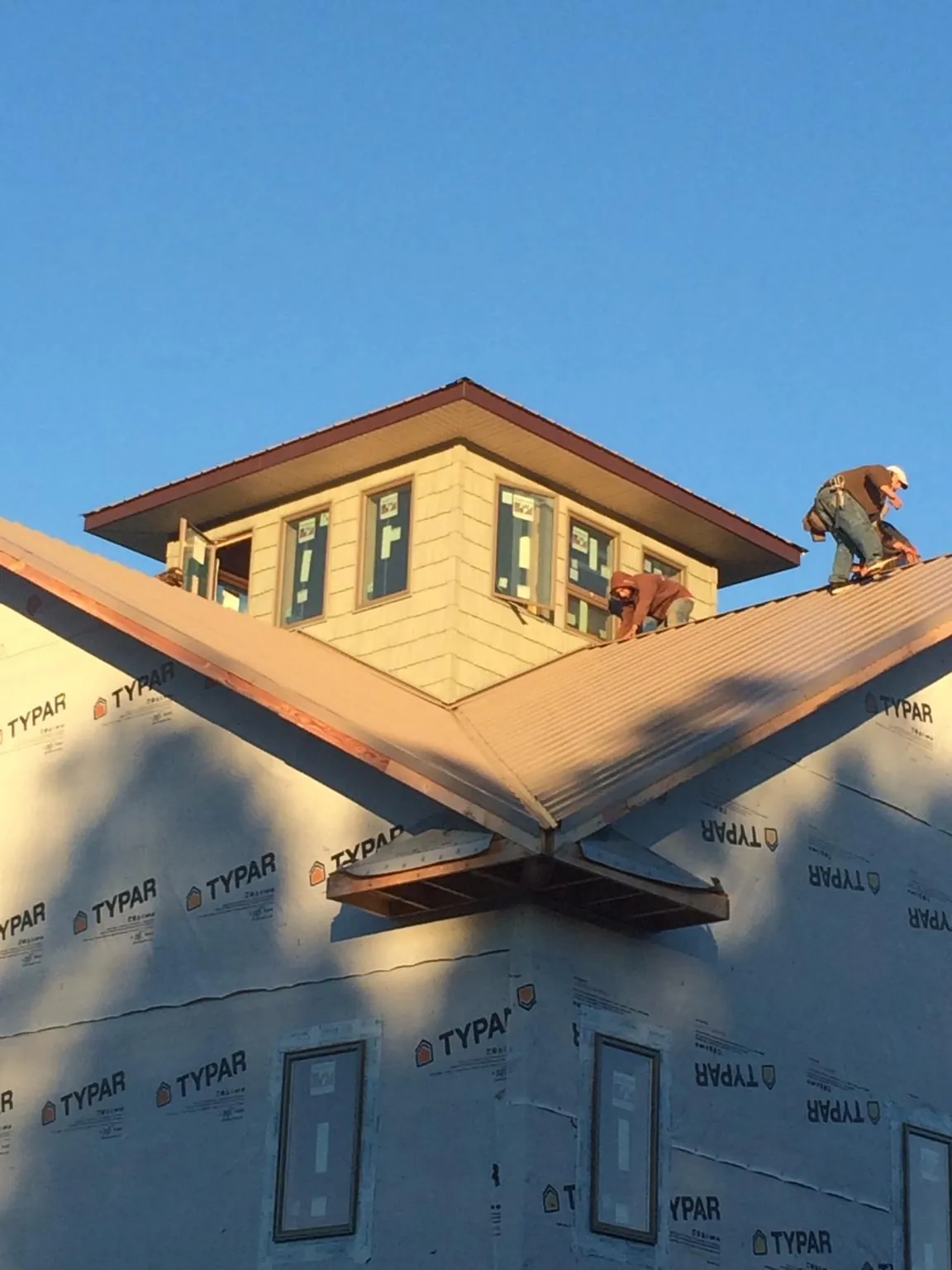 Roofers working around a rooftop cupola on a new metal roof at sunset — Roof Waterproofing in Kenedy by Roofing Brothers